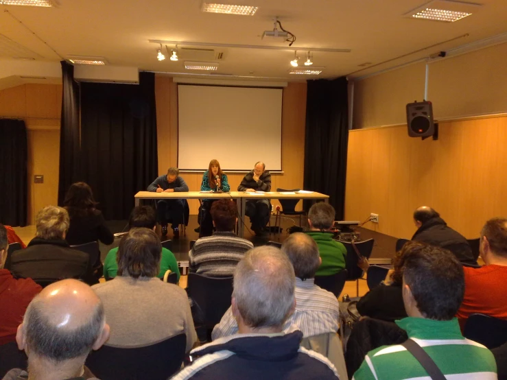 several people are sitting at tables in front of an audience