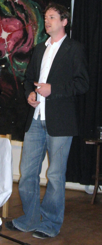 man in a black jacket and jeans holding a remote