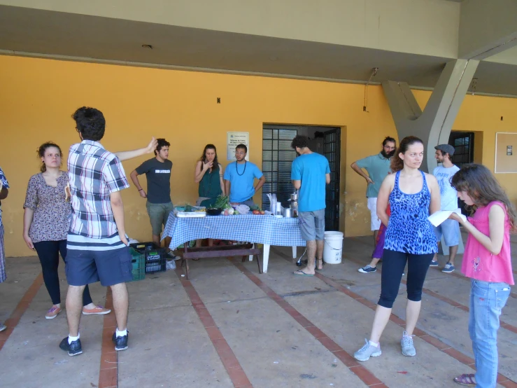 a group of people standing around tables next to yellow walls