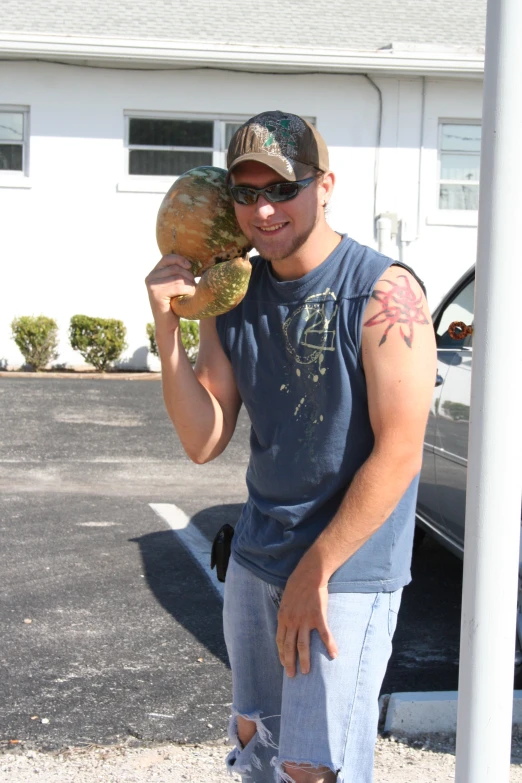 a man is holding up two pumpkins outside