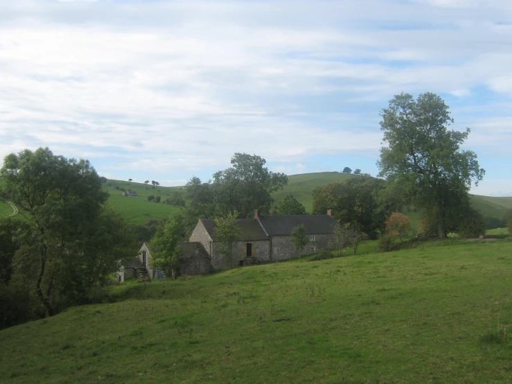 some houses on a hill with trees and clouds