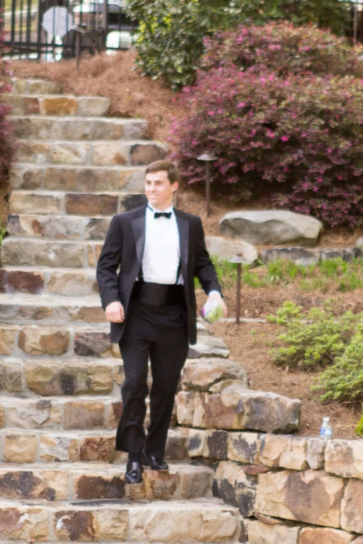 a man dressed in tuxedo is walking down the steps