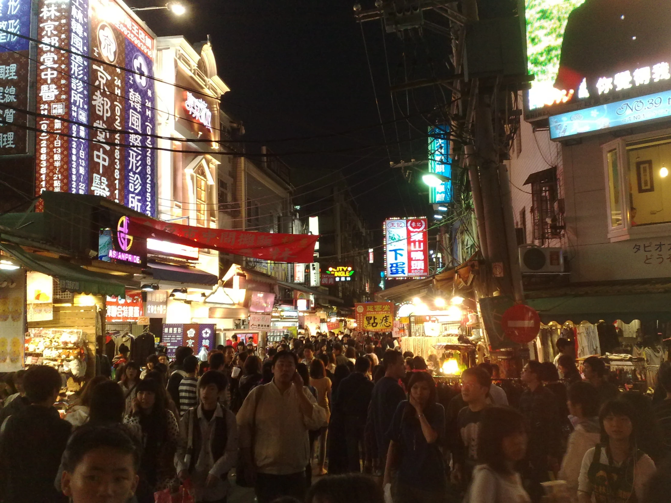 the crowded street at night has many people on it