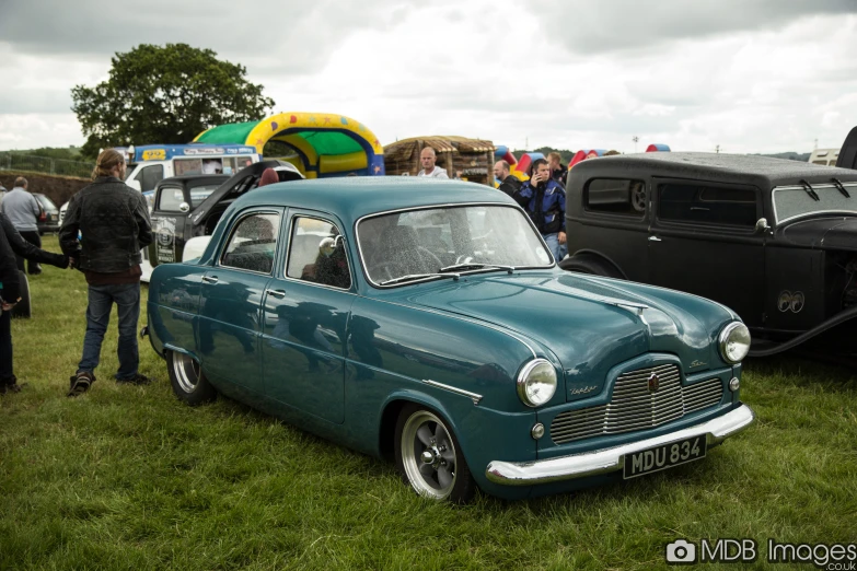 a blue car with chrome accents parked on a field