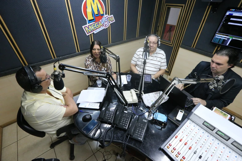 four people sitting in front of a desk with microphones