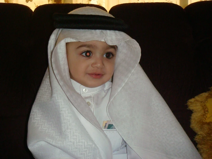 a little boy dressed up as a baby wearing a head piece