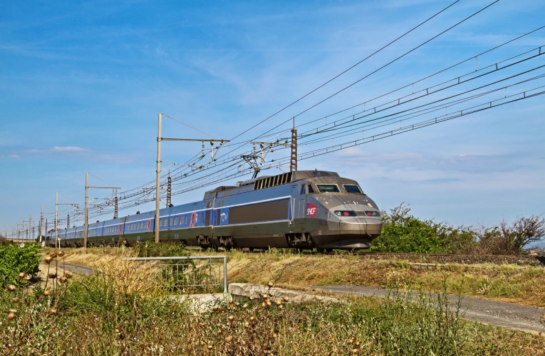 a passenger train traveling down tracks next to a hillside