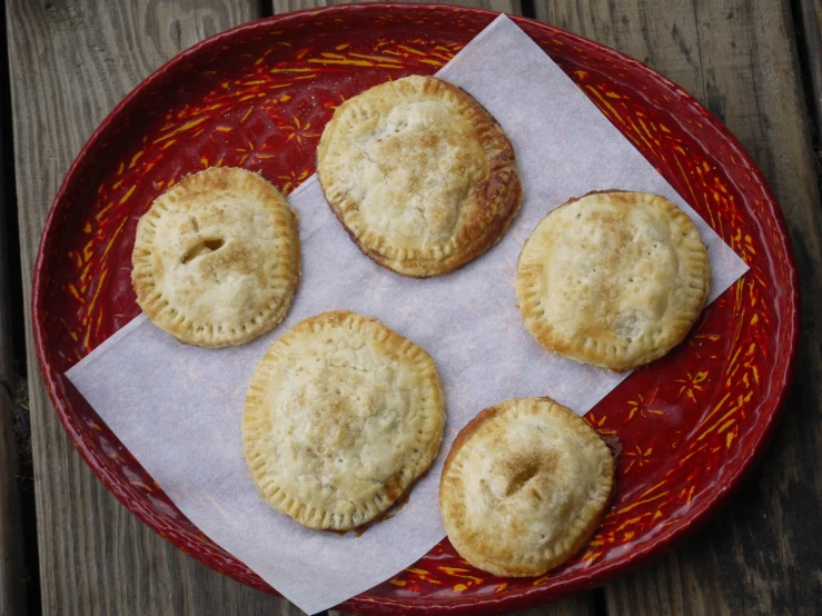 four pastries on a red dish on a wood table