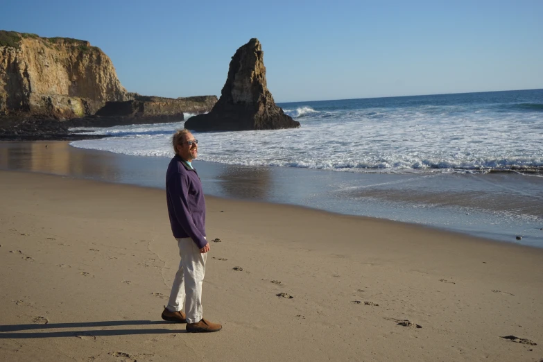 the man in shades is standing on the sand