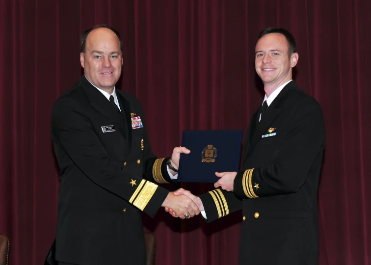 two military officers shaking hands, in uniform