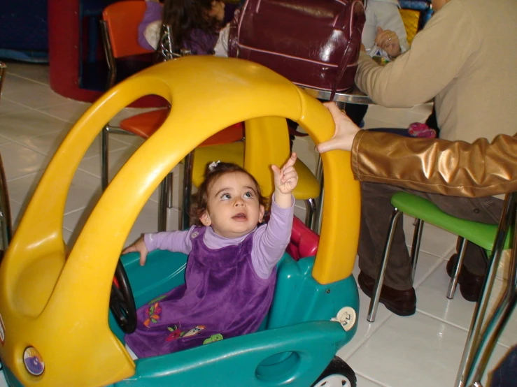 there is a little girl sitting in the small toy car