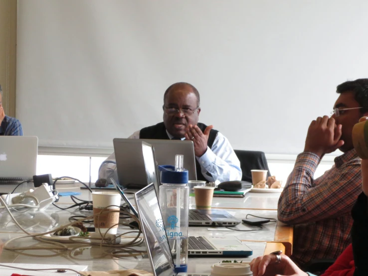 four people in a meeting at a table using laptop computers