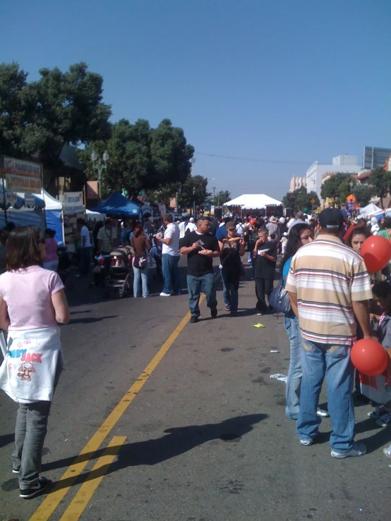 several people standing in the street with some balloons