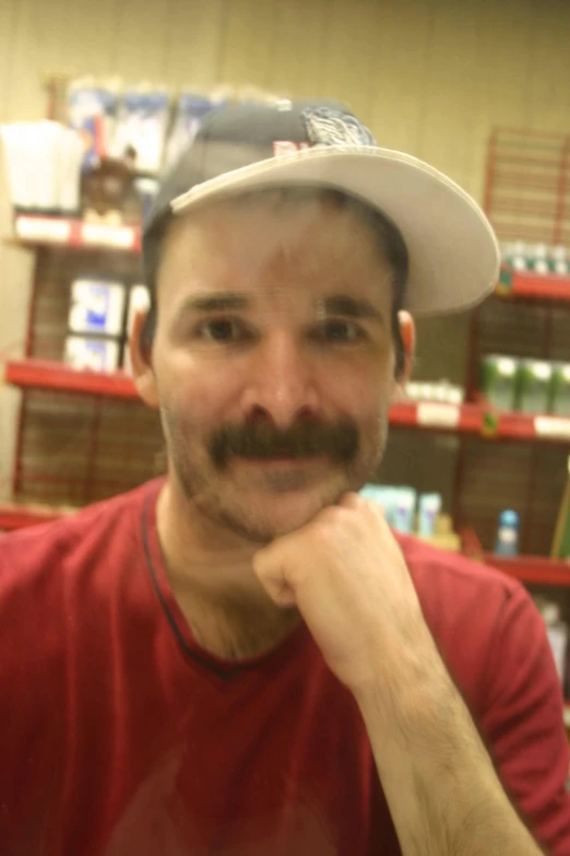 a man with a mustache sits in a store