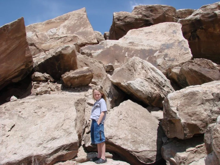 a girl standing next to rocks on the mountain