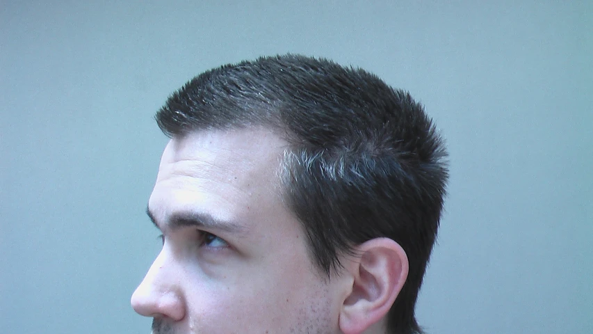 a young man with short dark hair staring upward