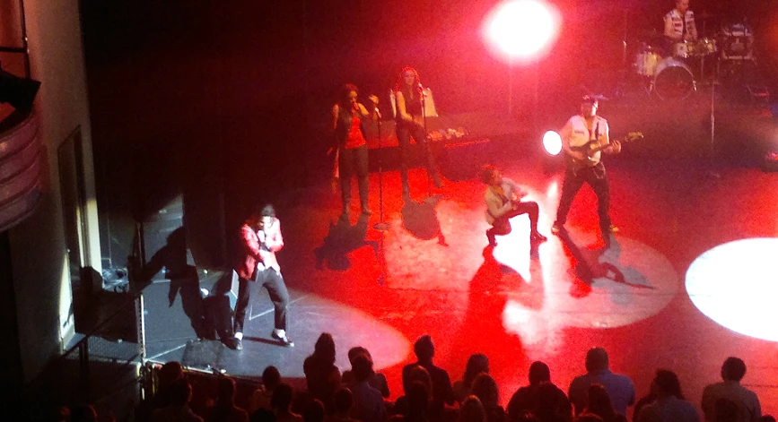 a group of people standing on top of a stage with a band on it