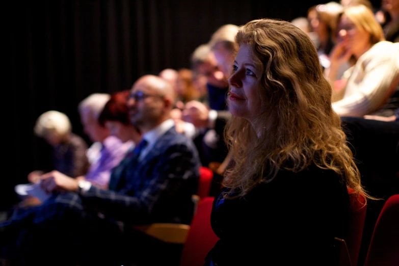 a woman is looking off to her left in the audience