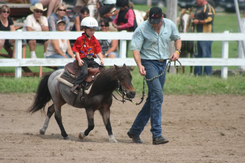 a woman leading a small child on the back of a horse