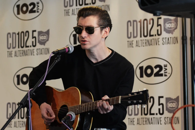 a man with sunglasses holding an acoustic guitar