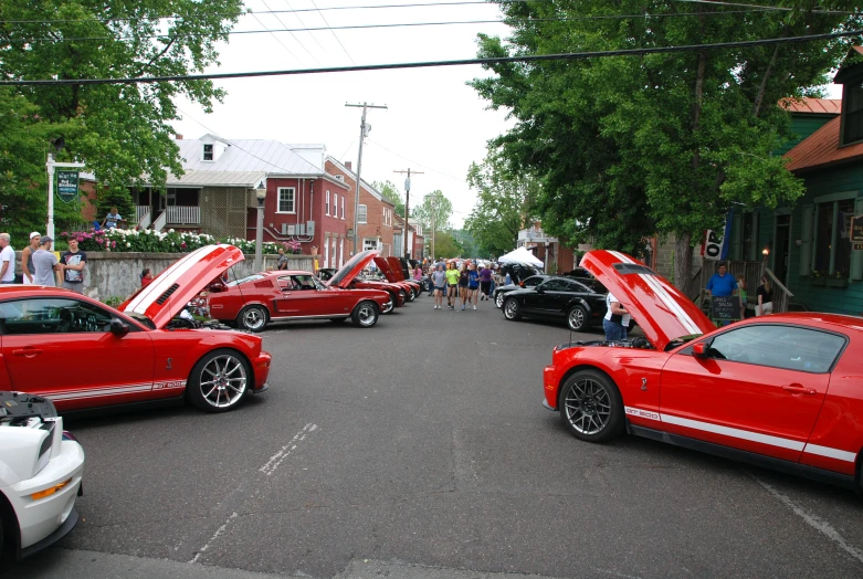 red car with open hood parked at the curb