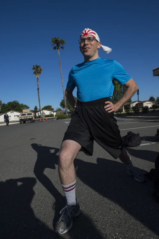 a man is standing in a parking lot, wearing shorts