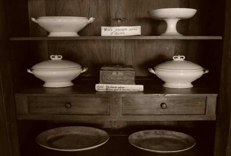 two white bowls sitting on top of a wooden shelf