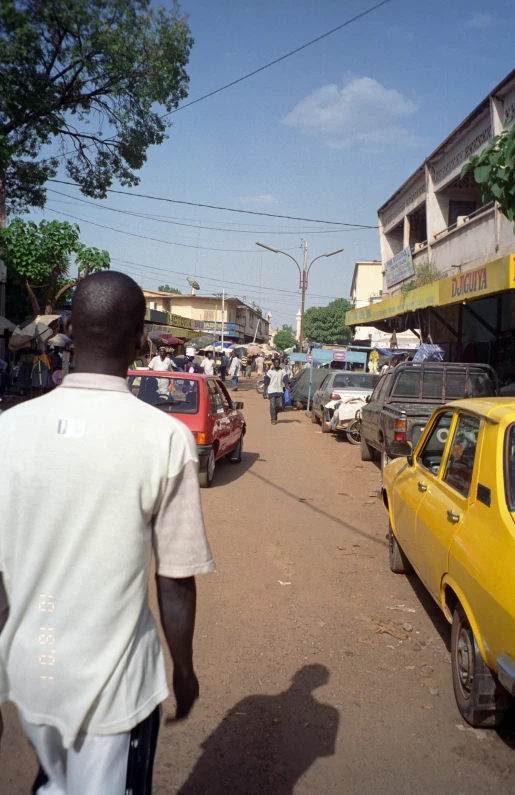 a man walks down an intersection with cars and buildings