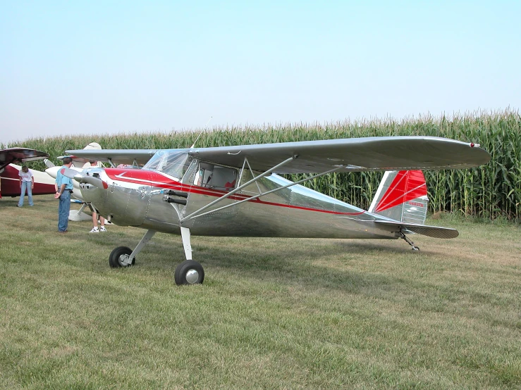 an older style prop plane in a field of corn