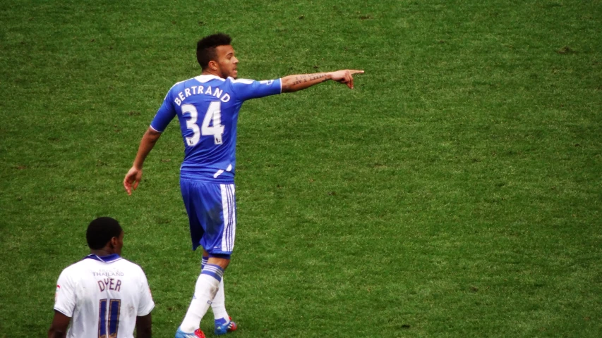 soccer player in blue kicking a soccer ball with three other players around