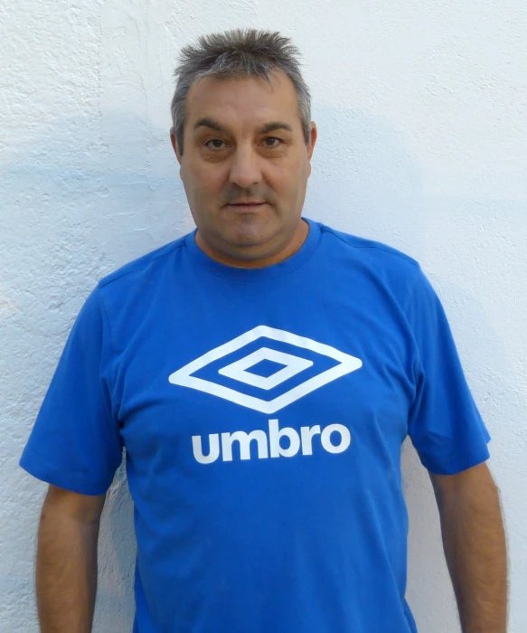 a man in a blue shirt standing by the side of a building