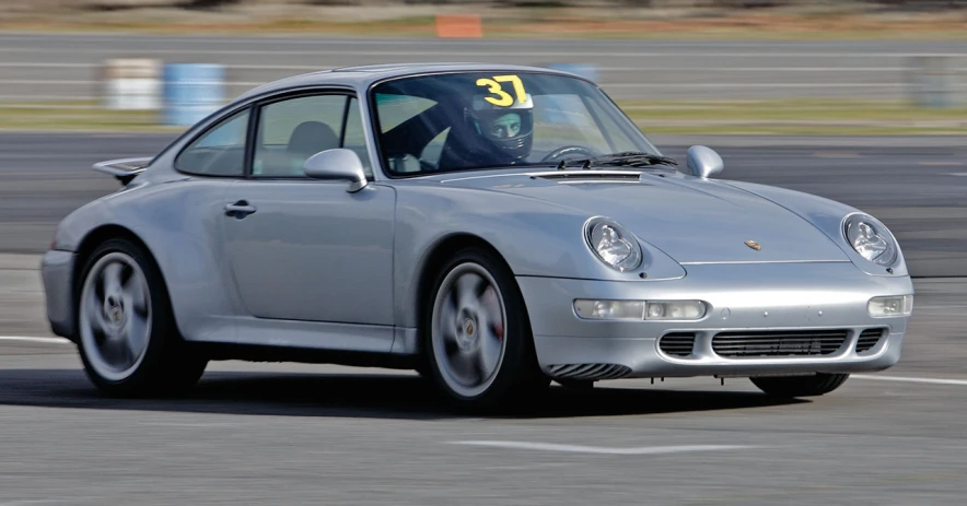 the silver porsche coupe driving down a track