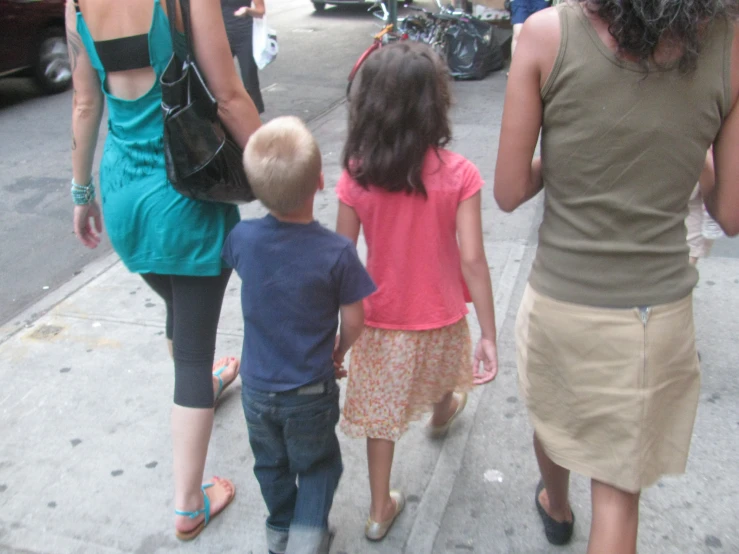 there are three children walking on the sidewalk