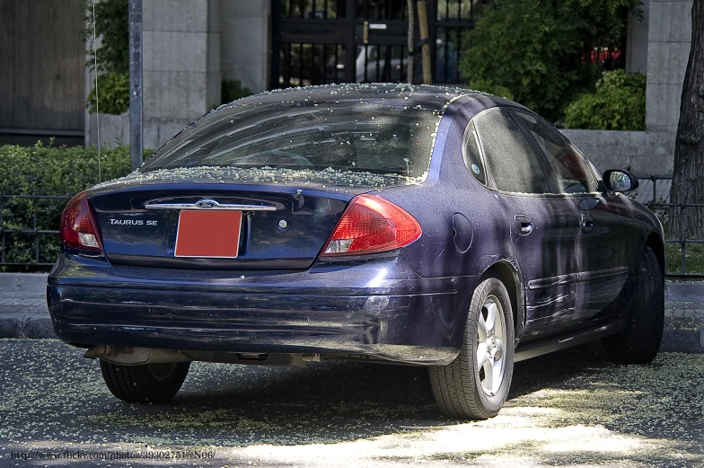 a blue sedan parked on the street has its back doors open