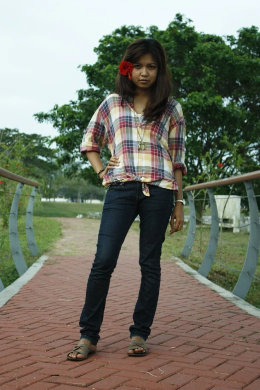 a woman standing on a bridge wearing denim jeans