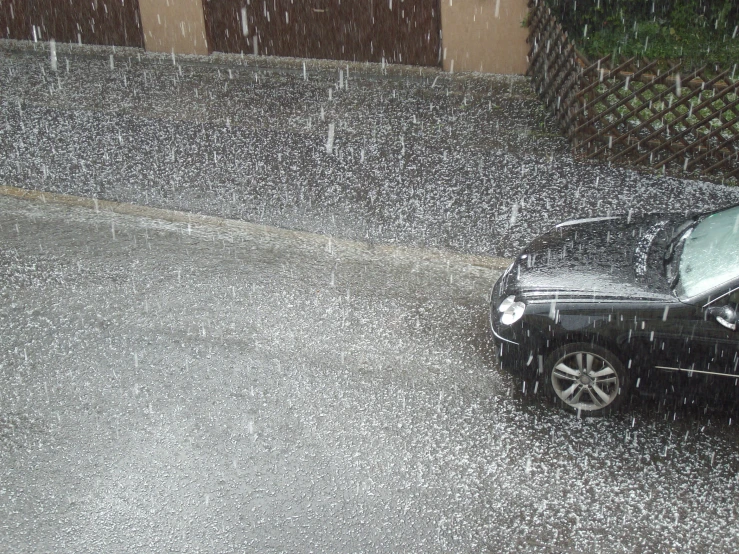 a car is parked at a curb under a rain