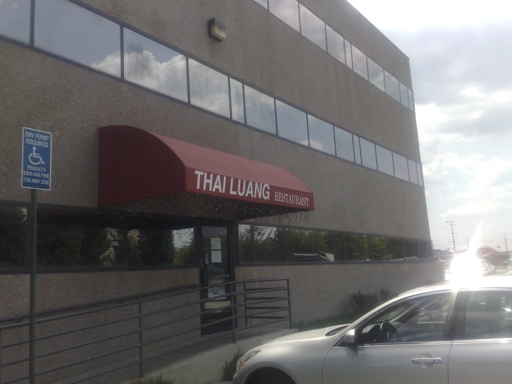 a silver car is driving next to the large building