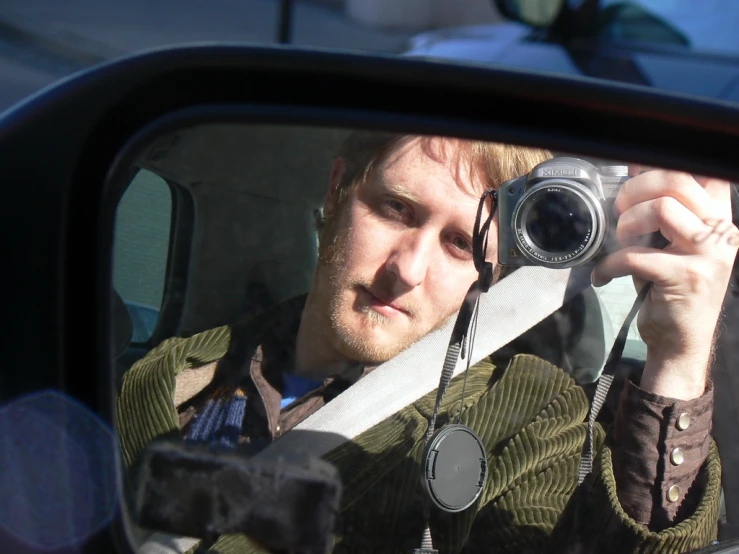 man taking a selfie in the rear view mirror