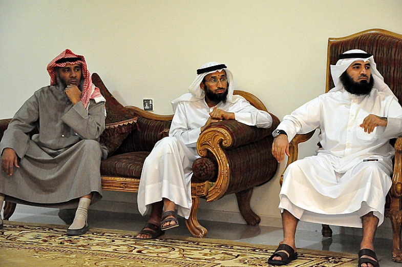 three men dressed in all white sit on a couch