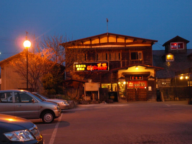 a couple of cars parked in front of a restaurant at dusk