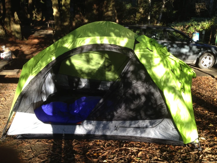 a large tent in the woods with cars parked