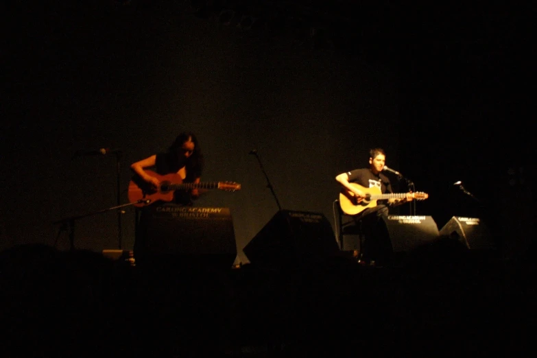 two people are on stage with guitars in front of them
