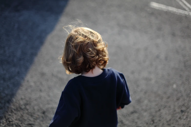 a little girl standing in the street looking down at soing