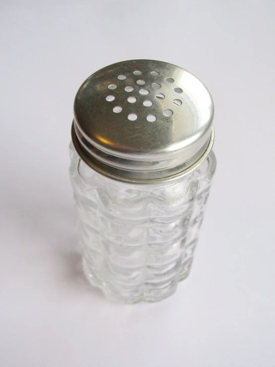 a salt shaker sitting next to a bottle of pills