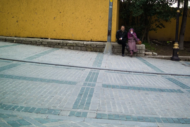 two people sitting in front of a yellow building