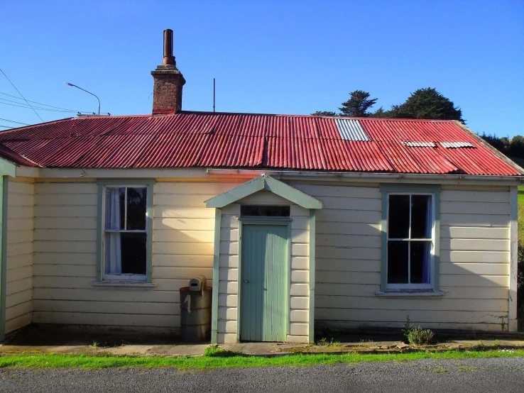 a small white brick cottage with red tile roof