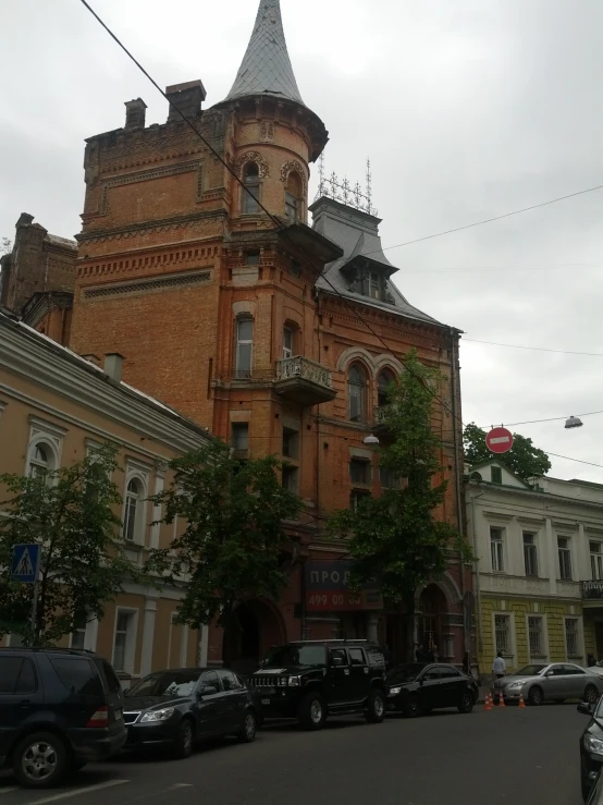 old castle like building with towers stands next to older townhouses