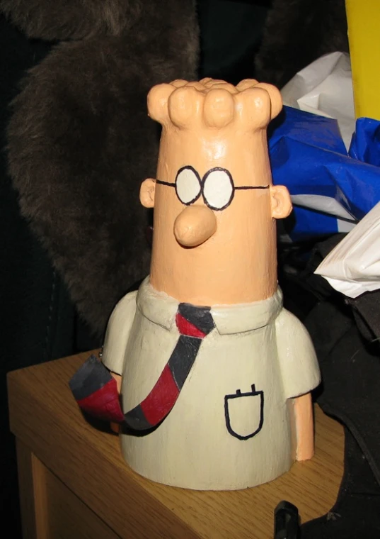a cartoon figure with glasses sits on a wooden block