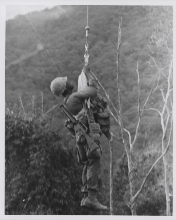 a black and white po of a man climbing up on a rope