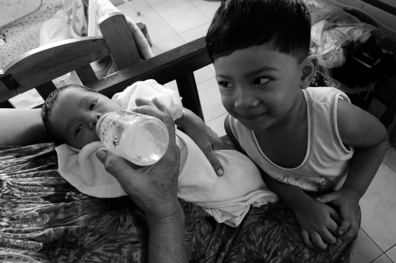 a little boy is holding a baby and drinking soing